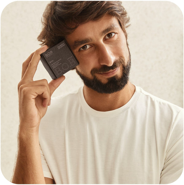 Man holding a box of Bars Over Bottles hair detox shampoo