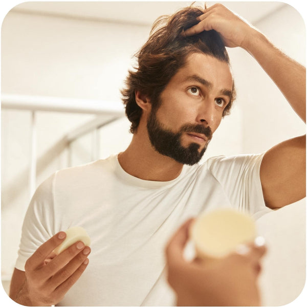 Man looking at his curly hair in a mirror and wants to know how often to use conditioner