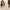 Woman in a white bathrobe looking at her reflection in a mirror while wondering what causes oily hair