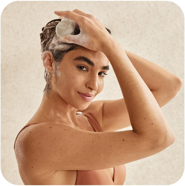 Young woman lathering her hair using what shampoo is best for oily hair