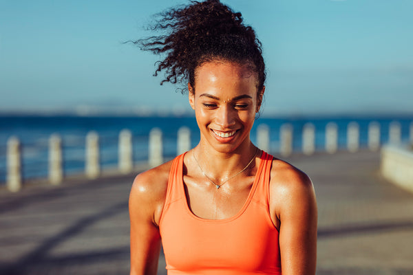 Woman in an orange tank top sweating while running early morning